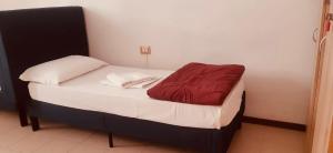 a small bed with a red blanket on it at My Friends in Florence