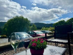 two glasses of wine sitting on a table with flowers at Carra Beag Guest House in Pitlochry