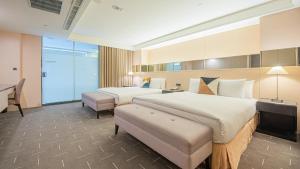 ein Hotelzimmer mit zwei Betten und einem Schreibtisch in der Unterkunft CHECK inn SELECT Taichung Dadun in Taichung