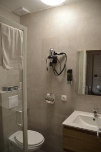 un bagno con un water, un lavandino e uno specchio di Hotel Mille Colonnes a Lovanio
