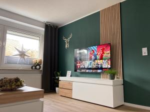 a living room with a flat screen tv on a green wall at Platzhirsch-bei-der-Purpurbuche in Bad Harzburg