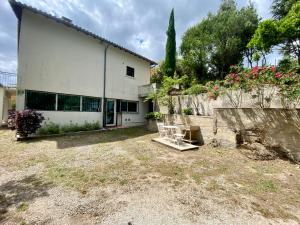 a white building with a fence and a yard at Appart 70m2 avec piscine in Saint-Geniès-de-Varensal