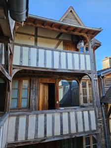 ein altes Holzhaus mit einer Katze, die auf dem Balkon sitzt in der Unterkunft Le Valentin - 2 chambres - 4personnes - 109m2 in Troyes