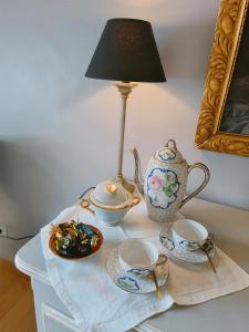 a table with a lamp and two cups and a tea pot at Suite familiale "Le Logis des Ptits Lynx" in Montain