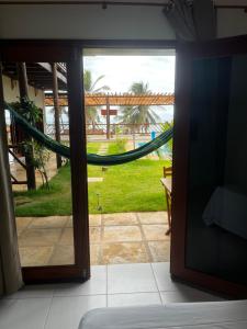 a room with a hammock and a view of a yard at Pousada Quinta do Mar in Icapuí