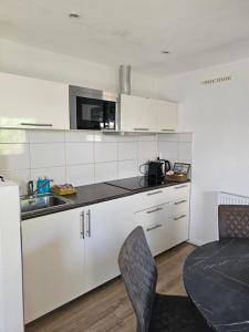a kitchen with white cabinets and a sink and a table at Witte Magnolia in Burgh Haamstede