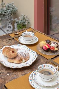 a table with plates of pastries and cups of coffee at Maison Bordoré in Faenza +27 photos
