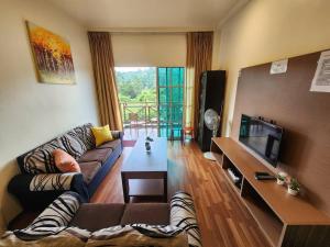 a living room with a couch and a tv at Iris Bougainvillea Cameron's in Tanah Rata