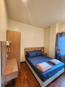 a bedroom with a bed with blue sheets and a window at Iris Bougainvillea Cameron's in Tanah Rata