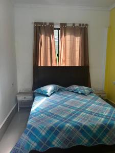 a bedroom with a bed with a plaid blanket and a window at Cantinho na roca com piscina in Santo Antônio do Pinhal