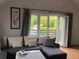 een woonkamer met een bank en een groot raam bij Apartament w Domu Wypoczynkowym Zacisze in Stegna