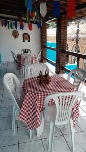 a table with white chairs and a red and white table cloth at Blue House in Lençóis
