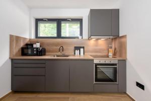 a kitchen with gray cabinets and a sink at Gorska Idila "Smreka" - a Modern House in Quiet Area with Wellness in Stari Laz