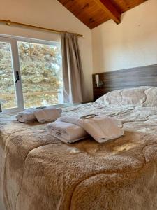 a bed with towels on it in a room with a window at Antu Mahuida Apartments in San Carlos de Bariloche