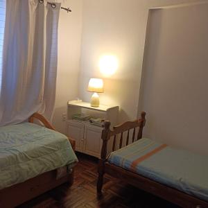 ein Schlafzimmer mit 2 Betten und einer Lampe auf einem Tisch in der Unterkunft Colonia Costanera in Colonia del Sacramento