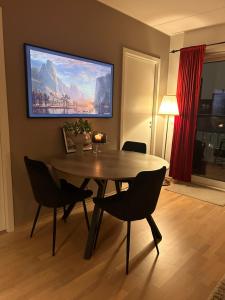 a dining room with a table and chairs and a painting on the wall at Moderne leilighet i Lørenveien in Oslo