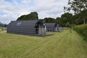 a group of black buildings in a field at Oakwood Escapes in North Cliff