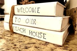 uma pilha de livros com as palavras bem-vindo à nossa casa de praia em TipSea Turtle 3 Community pools Central Destin em Destin mais 43 fotografias