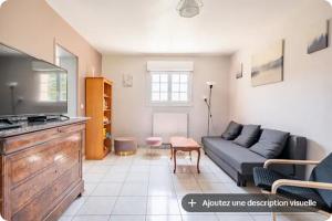 a living room with a couch and a tv at Gîte du Coudray in Neuillé-Pont-Pierre