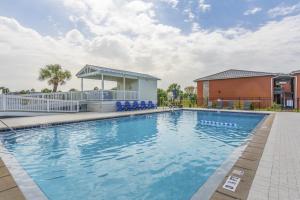 una piscina con sedie blu e un edificio di Captains Quarters 3 Comm Pools Pet Friendly a Destin
