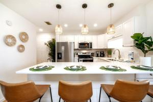 a kitchen with white cabinets and a large island with chairs at Eden Escape Lake View 3 Pools Pet Friendly in Destin
