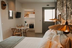 a bedroom with a bed and a table and a kitchen at Venue Villas - Folegandros in Áno Meriá