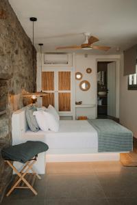 a bedroom with a white bed and a chair at Venue Villas - Folegandros in Áno Meriá
