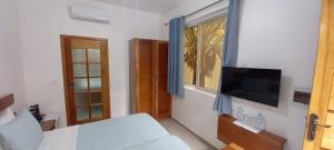 a bedroom with a bed and a flat screen tv at Hotel Viajante in Tarrafal