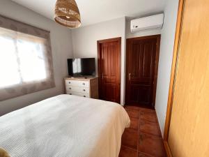 a bedroom with a white bed and a television at Casa con piscina en Málaga in Sierra de Yeguas +17 photos