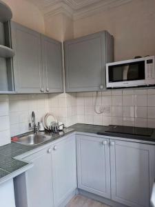 a kitchen with white cabinets and a microwave and a sink at Bright Studio Apartment in a perfect location in London