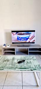 a room with a tv and a table with a glass table sidx sidx at Appartement plein centre-ville in Lodève