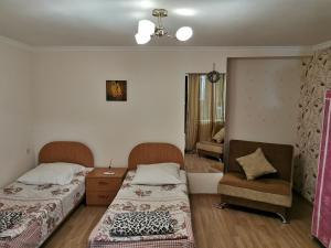 a room with two beds and a chair in it at Guest House Natia in Tbilisi City