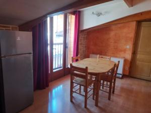a kitchen with a wooden table with chairs and a refrigerator at Le charme montagnard in Barcelonnette +4 photos
