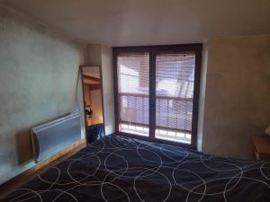a bedroom with a large bed and two windows at Le charme montagnard in Barcelonnette