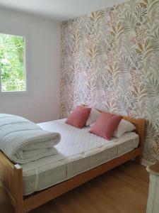 a bed with two pink pillows in a bedroom at Gîte le Vieux Moulin in Sansais