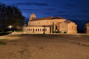 a large stone church with a cross in front of it at Casas Rurales Mi Reja B in Santa María de Riaza +4 photos
