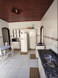 a large kitchen with white appliances and a table at Casa vila do serrano in São Bento do Sapucaí