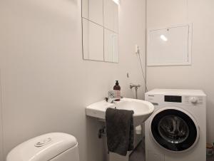 a white bathroom with a washing machine and a sink at Green appartement in Sandnes