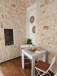 a white table and chairs in a room with a stone wall at PietraRosa Apartment in Triggianello