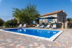 マリンスカにあるStone house Villa Liviaの建物の隣にプール(椅子、パラソル付)