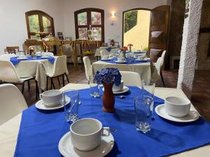 a dining room with white tables with blue table cloth at Suíte Master conforto e espaço vizinha do Palácio de Cristal! in Petrópolis