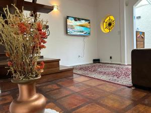 a living room with a vase with flowers in it at Suíte Master conforto e espaço vizinha do Palácio de Cristal! in Petrópolis