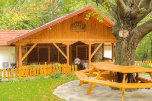 a wooden cabin with a picnic table in front of a tree at Вила Деа in Kotel