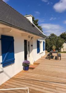 une maison avec une terrasse en bois et une table dans l'établissement Maison bretonne rénovée à neuf - Terrasse plein sud - Proche plage, à Perros-Guirec