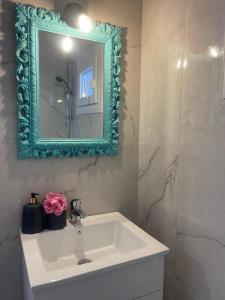 une salle de bain avec un lavabo blanc et un miroir vert dans l'établissement Silvia, à Skala Sotiros