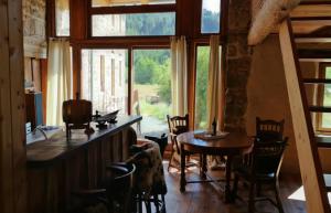 a room with a table and chairs and a large window at Afgelegen gite naast rivier omringd door bossen in bergachtige omgeving in Saint-Bonnet-le-Chastel