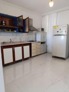 a kitchen with a white refrigerator and a white tile floor at Adenaz Apartmanları tatil köyü in Erdemli