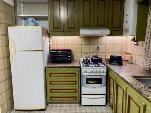 a kitchen with green cabinets and a white refrigerator at Alquiler Temporario Las Parejas in Las Parejas