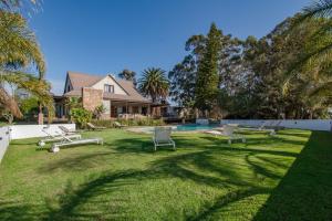a yard with lounge chairs and a house at Kana guest farm - 35 rooms for 70 guests in Stellenbosch