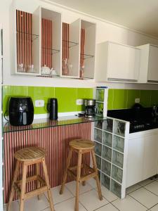 a kitchen with two bar stools and white cabinets at Residencial Neo 1 in Maceió +8 photos